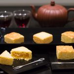 Taiwanese pineapple cakes in serving dish, individual ones on plates, and tea and tea pot behind