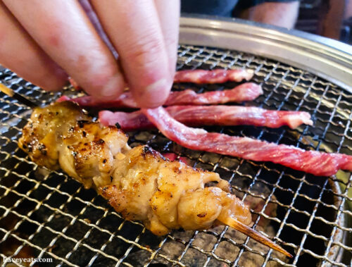Chicken skewers and sliced beef grilling on table-top barbeque