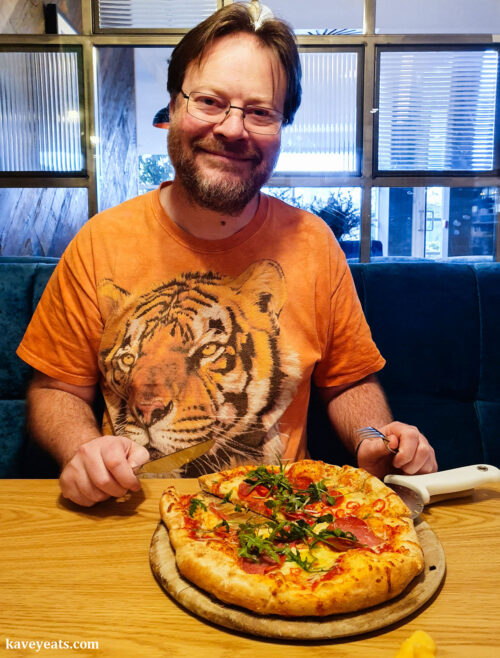 Pete eating Salami, pepperoni, red chilli and rocket pizza